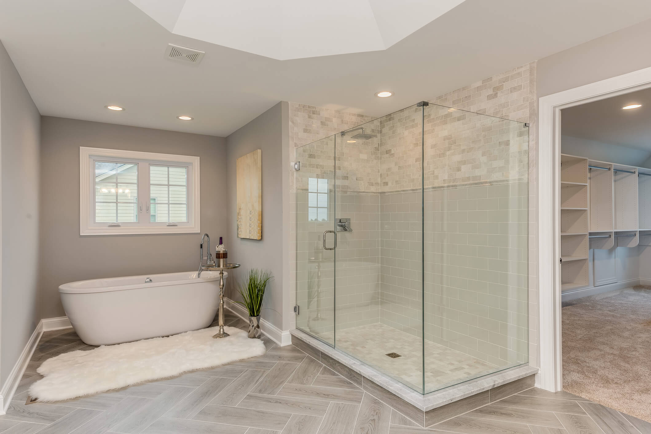 Primary bathroom with freestanding tub, glass shower and herringbone tile floor